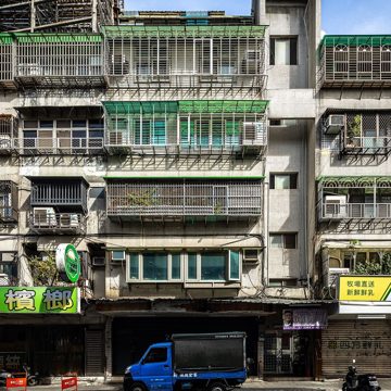 台北果菜市場外的街道，一樓是傳統市場，門口停著送貨的小貨車